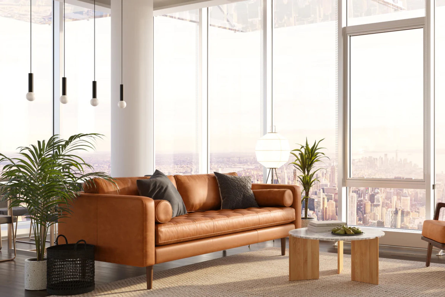 A stylish living room with floor-to-ceiling windows showcasing a city skyline. It features a caramel brown leather sofa with cushions, a round wooden coffee table with a decorative item, hanging pendant lights, and lush green plants.