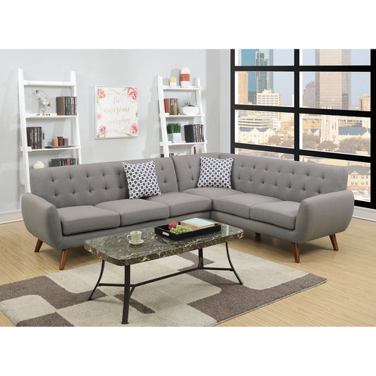 A contemporary living room featuring a Retro Modern Grey Sectional Sofa in an L-shape, adorned with patterned cushions. It includes a marble coffee table and a geometric rug. Against the wall, there's a white shelving unit filled with books and decor, while a large window provides a view of the cityscape.