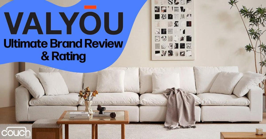 A cozy living room features a large white sectional sofa with a light gray throw draped over it. A wooden coffee table with flowers and a magazine is in front. The wall displays monochrome art. Text reads "Valyōu: Ultimate Brand Review & Rating.