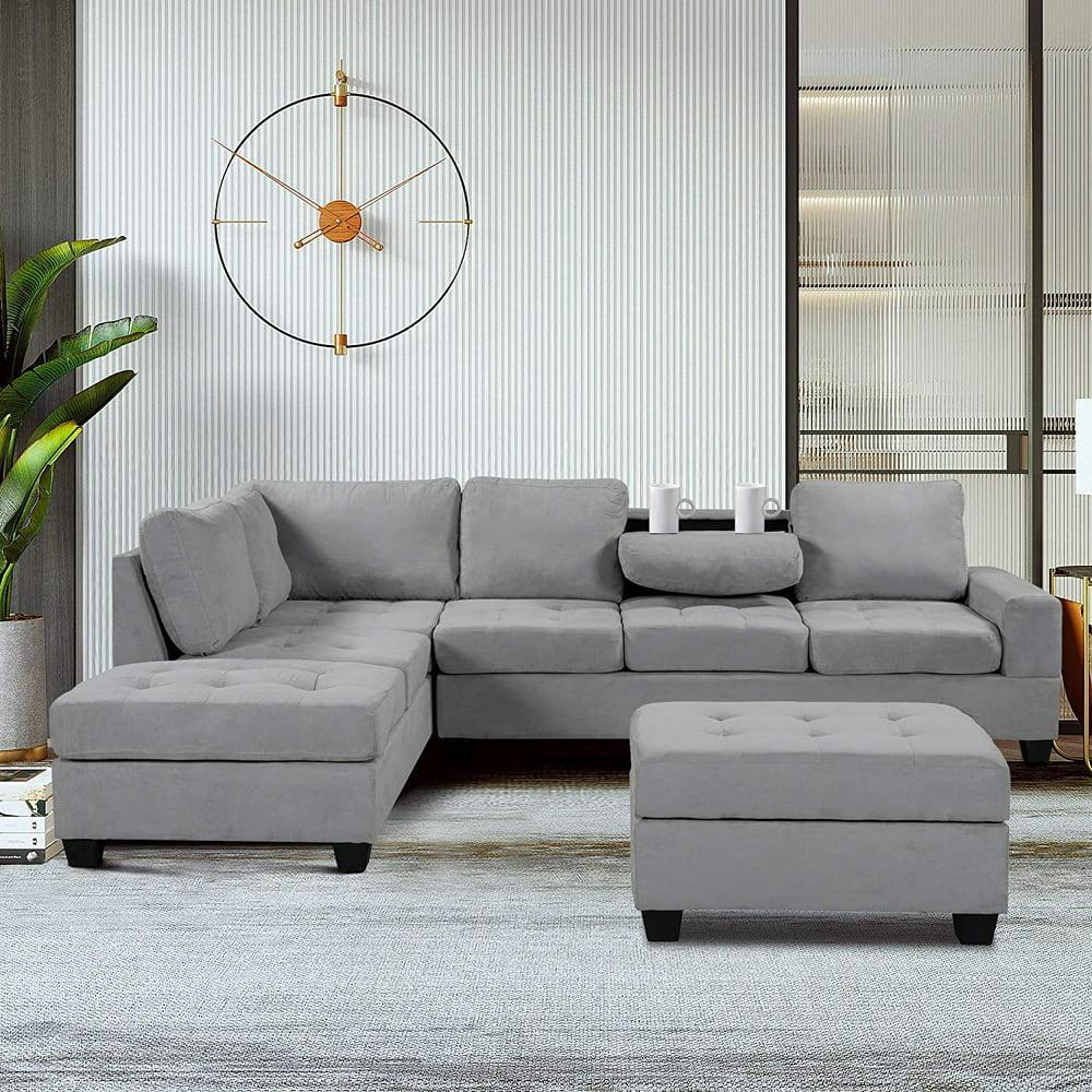 A modern living room features a plush gray sectional sofa with an ottoman. The sectional has a chaise lounge on the left side. A stylish wall clock and tall green plant accent the room. Neutral tones and soft lighting create a cozy atmosphere.