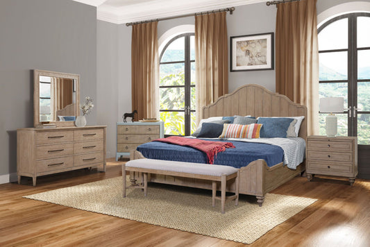 A cozy bedroom features the Panel Bedroom Set with 3 Drawer Nightstand, Casual Dresser, Cane Mirror, 3 Drawer Cane Front Chest, and Bench. Large arched windows with brown curtains and a rug complete the warm, inviting space.