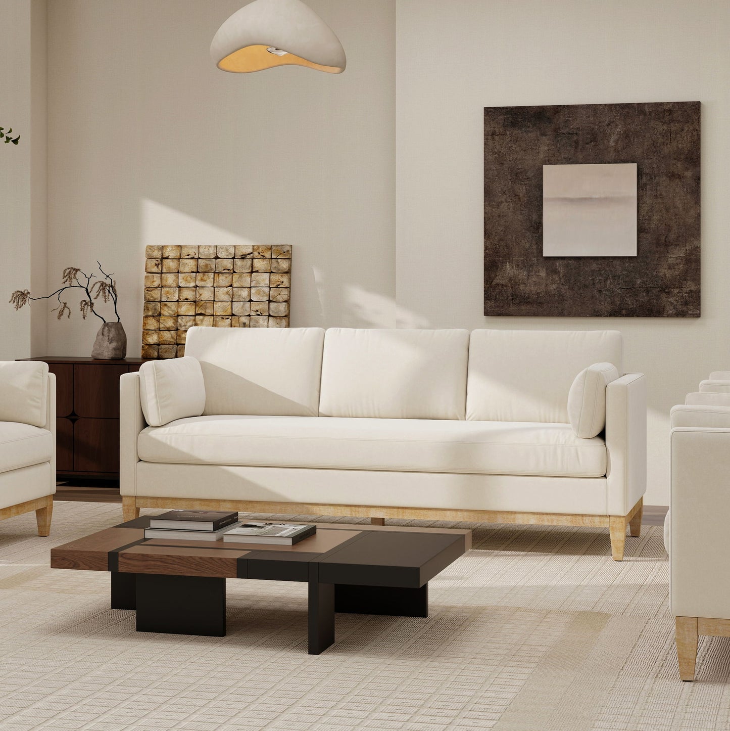 A modern living room featuring the Knox - Modern Farmhouse Sofa in white, a matching armchair, low wooden coffee table, abstract wall art, and neutral beige and brown decor. A dried plant rests on the sideboard beside the sofa.
