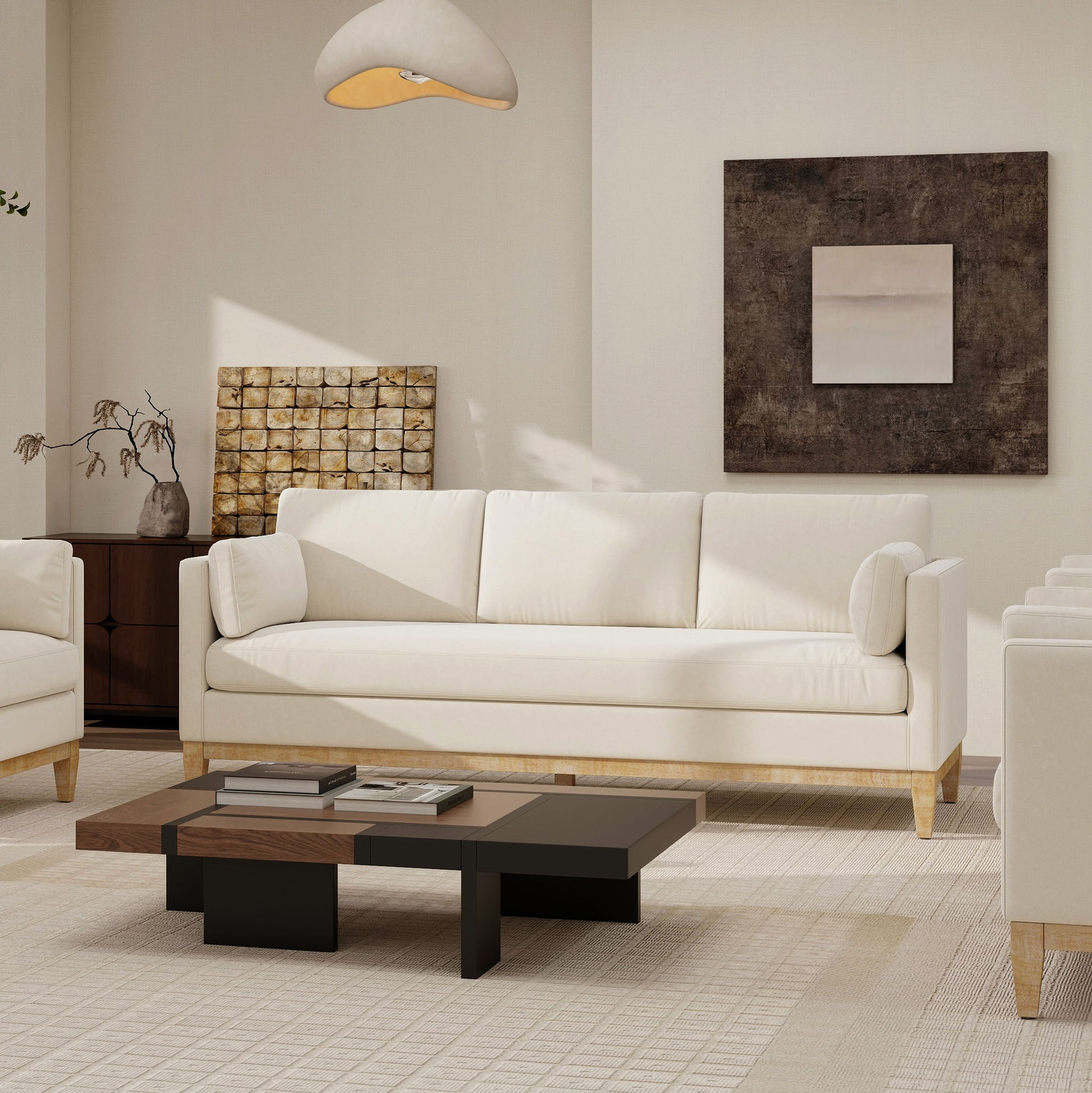 A modern living room featuring the Knox - Modern Farmhouse Sofa in white, a matching armchair, low wooden coffee table, abstract wall art, and neutral beige and brown decor. A dried plant rests on the sideboard beside the sofa.