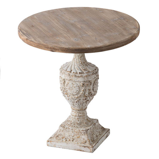 The Antique Round Wood Table features a rustic gray wood top and an ornate, distressed antique white pedestal base with decorative carvings and a square foot.
