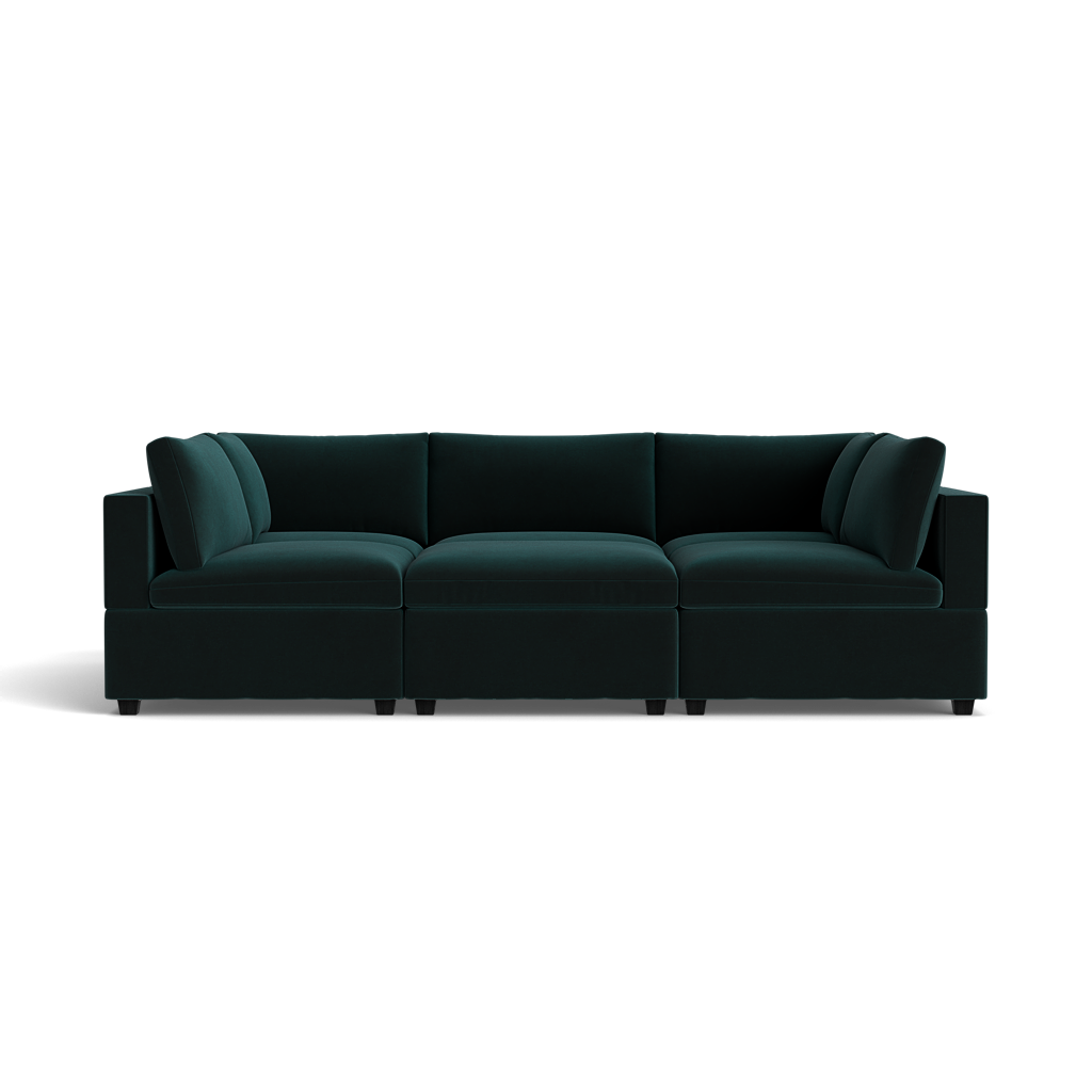 The Kova Box Cushion Pit is a dark green velvet sectional sofa with deep cushions, wide armrests, and modern lines, displayed against a plain black background.