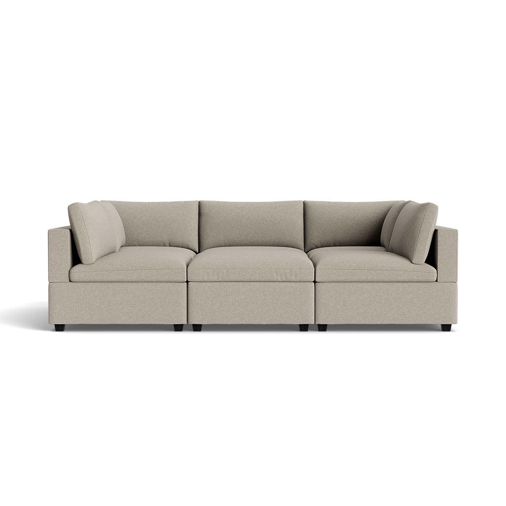 The Kova Box Cushion Pit is a modern sectional sofa in light beige, featuring three wide seat and matching backrest cushions, shown against a plain black background.