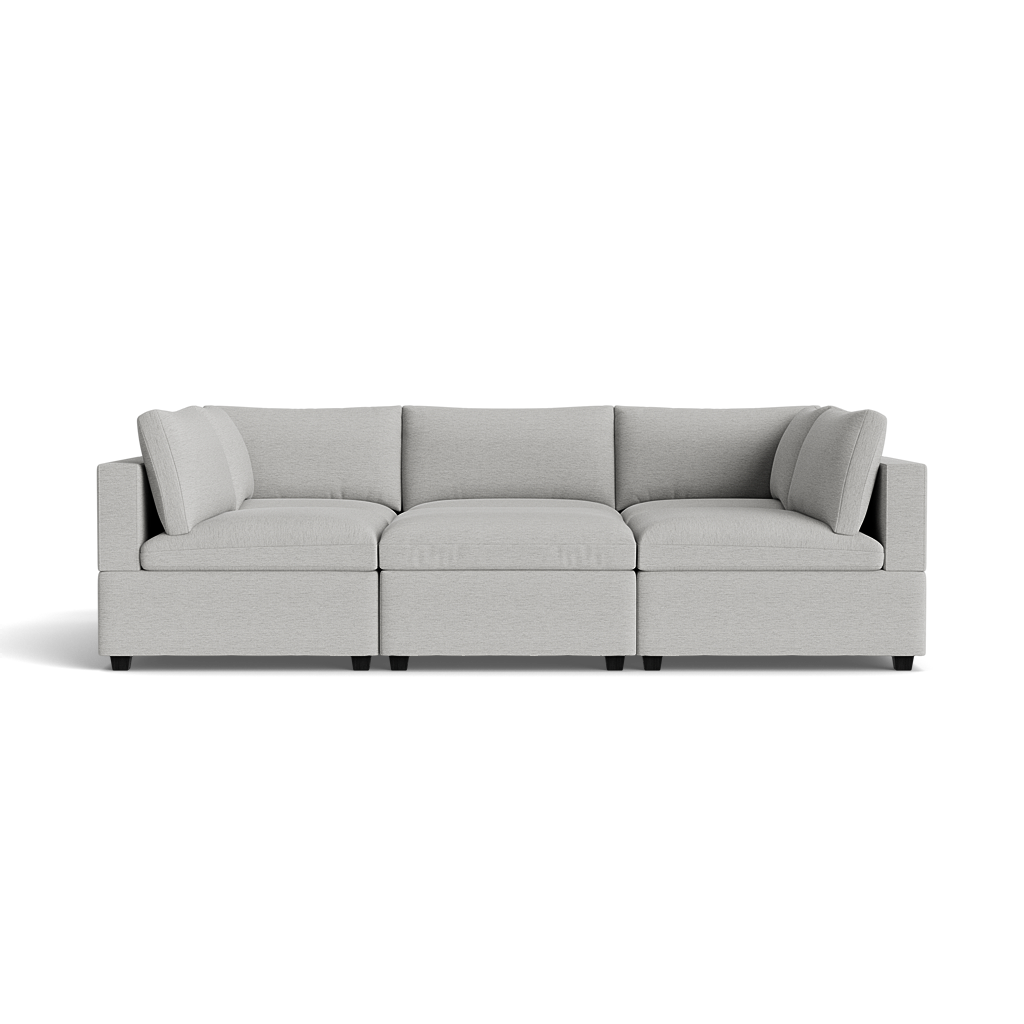 The Kova Box Cushion Pit is a modern light gray sectional with three connected seats and matching back and side cushions, set against a plain black background.