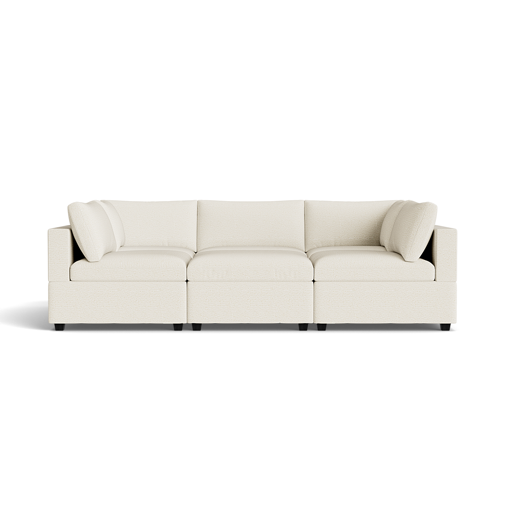 The front view of the Kova Box Cushion Pit, a modern three-seat cream-colored sofa with square arms and matching back cushions, set against a plain black background.