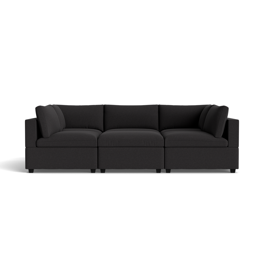 The Kova Box Cushion Pit is a modern dark gray sectional sofa with three seat cushions, angled armrests, and plush back cushions, displayed against a black background.