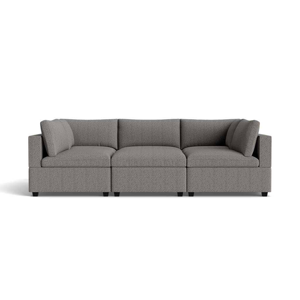 The Kova Box Cushion Pit is a modern gray three-piece sectional sofa with plush cushions and armrests at both ends, shown against a black background.