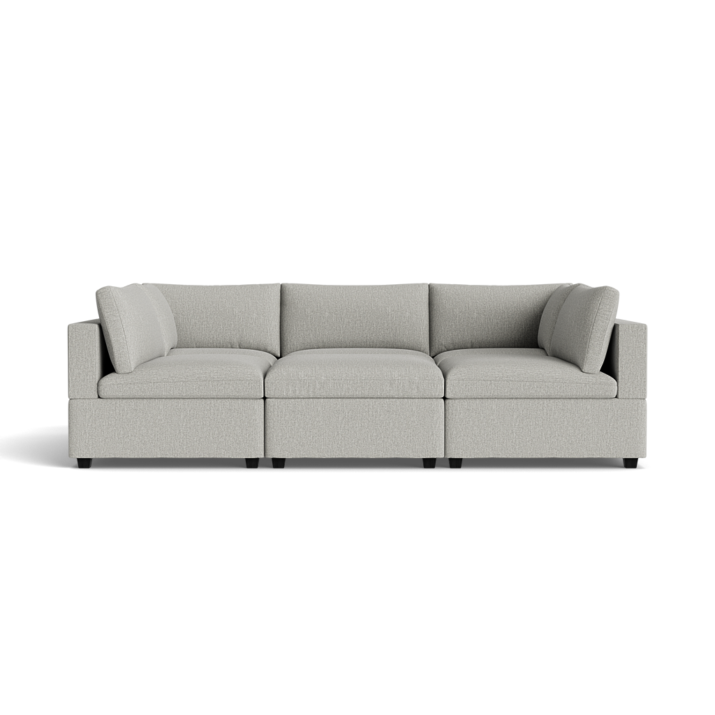 The Kova Box Cushion Pit is a modern, light gray, L-shaped sectional sofa with plush cushions and armrests on both ends, shown against a plain black background.