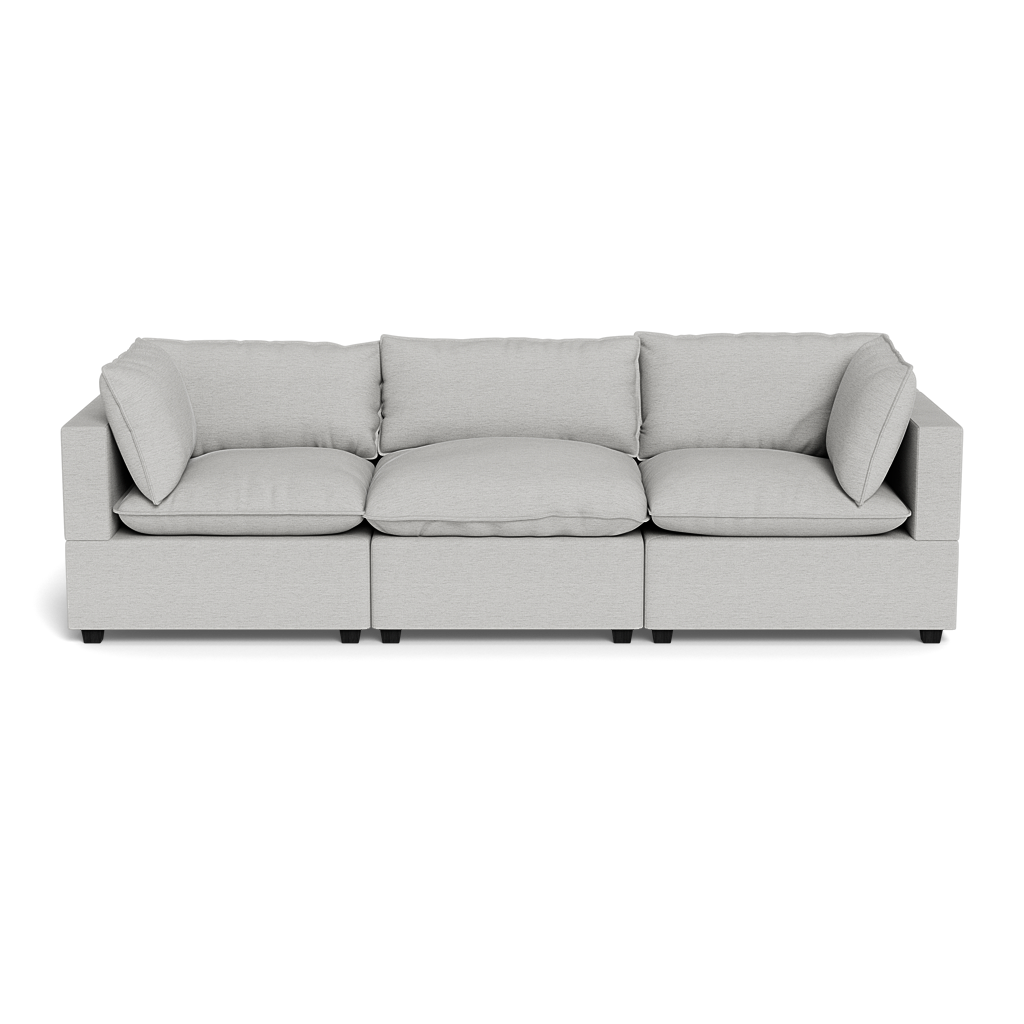 The Kova Pillow Cushion Sofa 122" is a modern, light gray three-seater with square arms and five cushions, shown from the front on a black background.