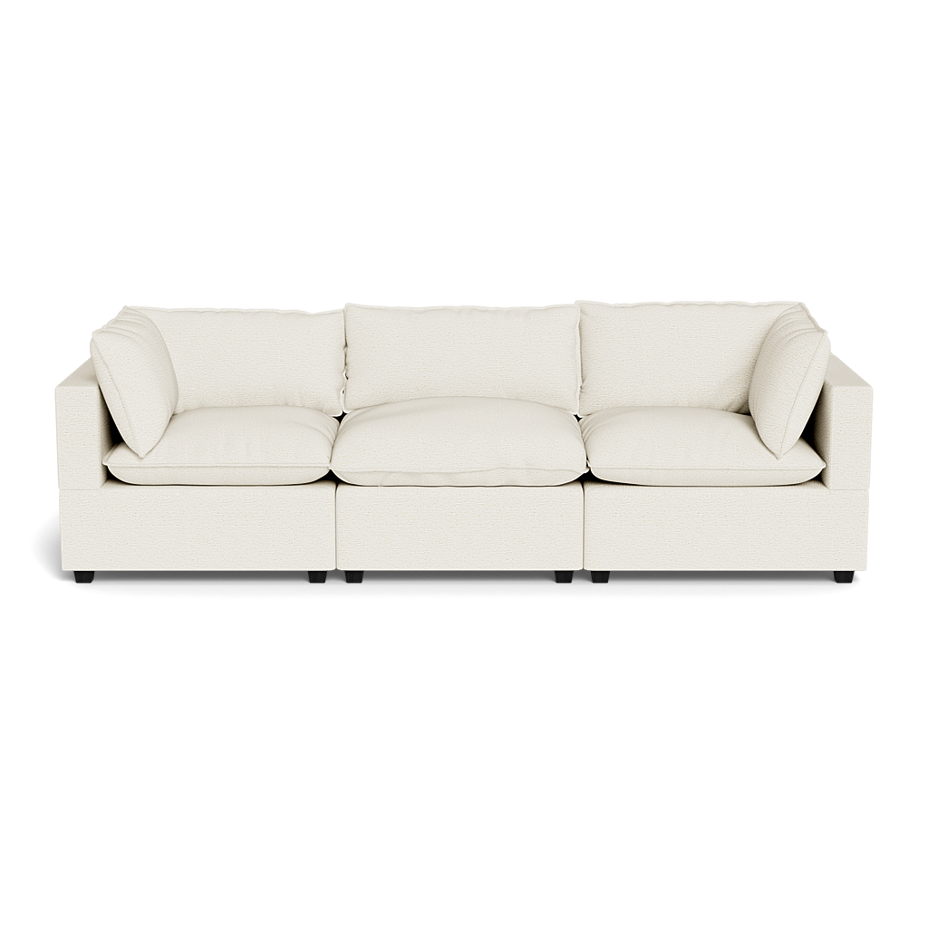 The Kova Pillow Cushion Sofa 122" is a modern, light beige three-seater with square arms and matching cushions, shown against a plain black background.