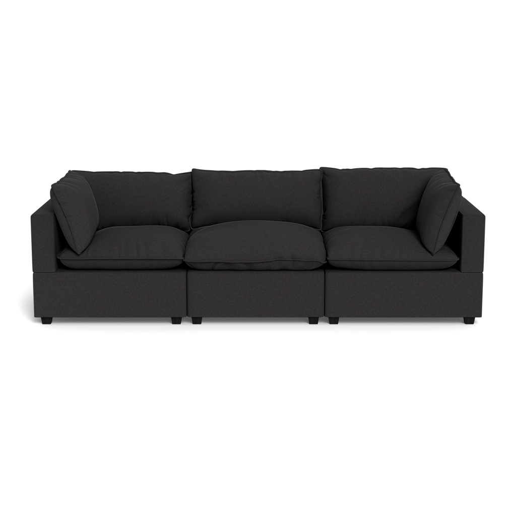 The Kova Pillow Cushion Sofa 122" is a modern black three-seater with square armrests and backrest, featuring three seat cushions and three large back cushions, displayed on a black background.