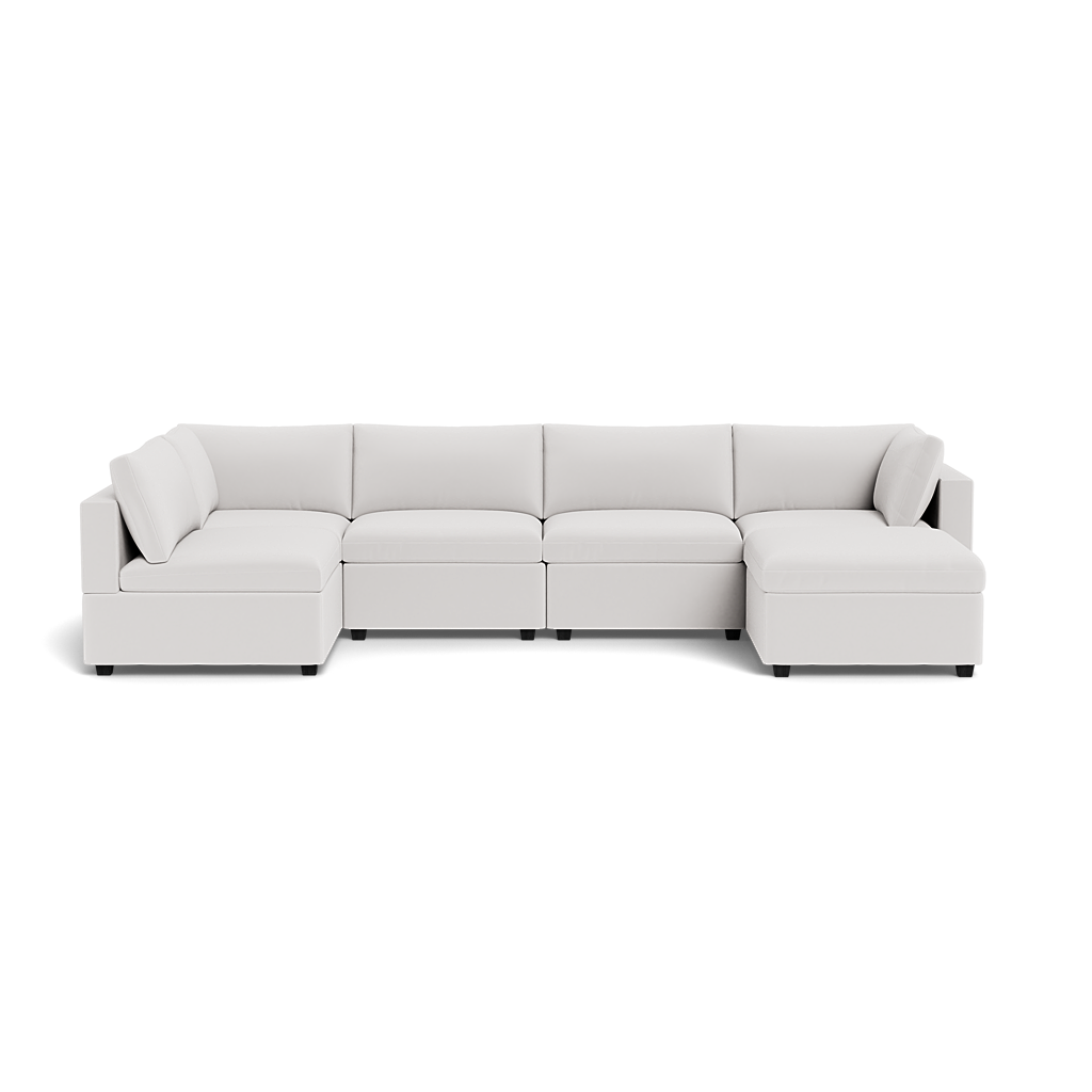 The Kova Box Cushion U-Shape is a modern white sectional sofa with five seats, two armrests, low backrests, clean lines, and a minimalist design. It includes two matching cushions and is shown against a plain background.