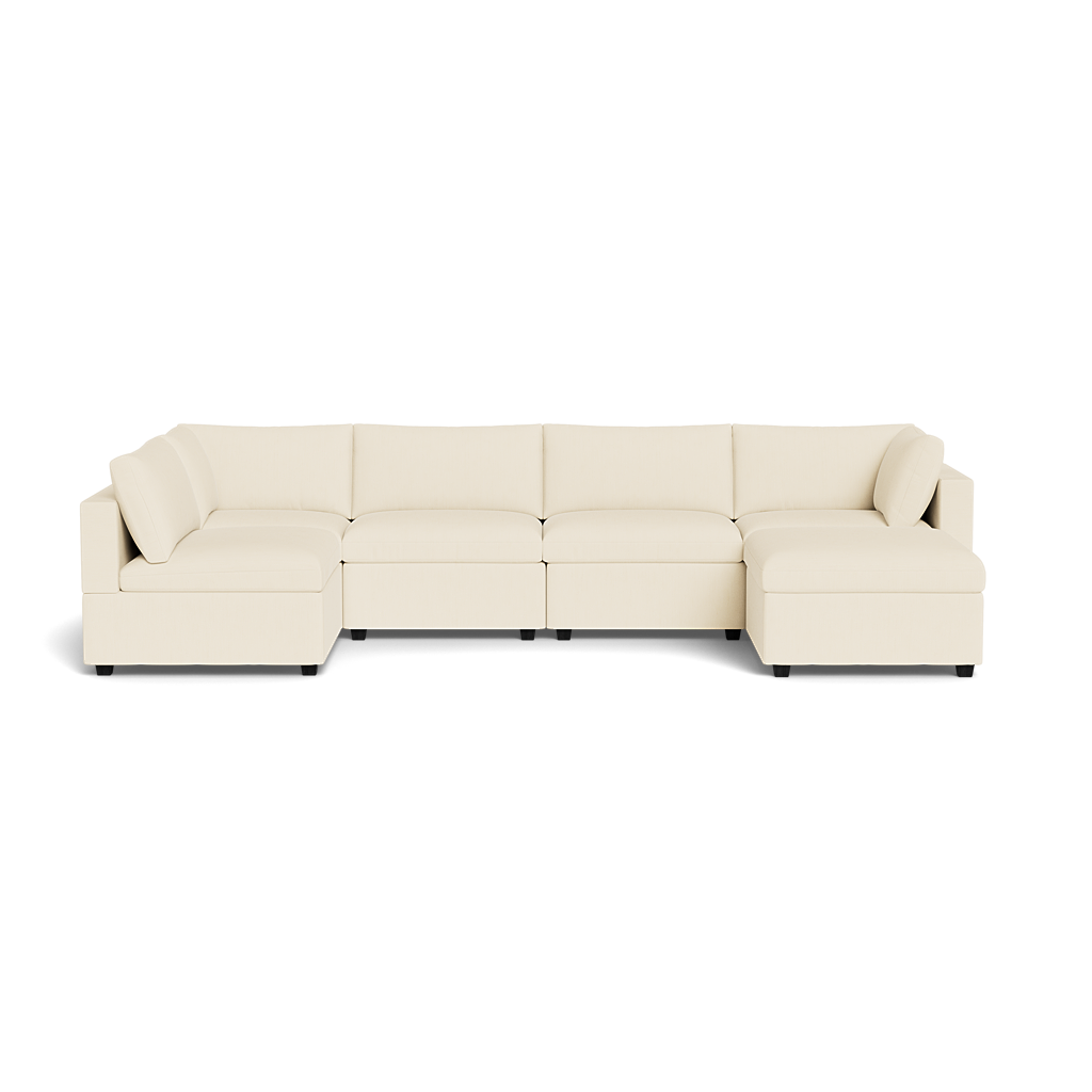 The Kova Box Cushion U-Shape is a large, modern beige sectional sofa with low backrests and cushions, featuring a chaise lounge at both ends, set against a plain white background.