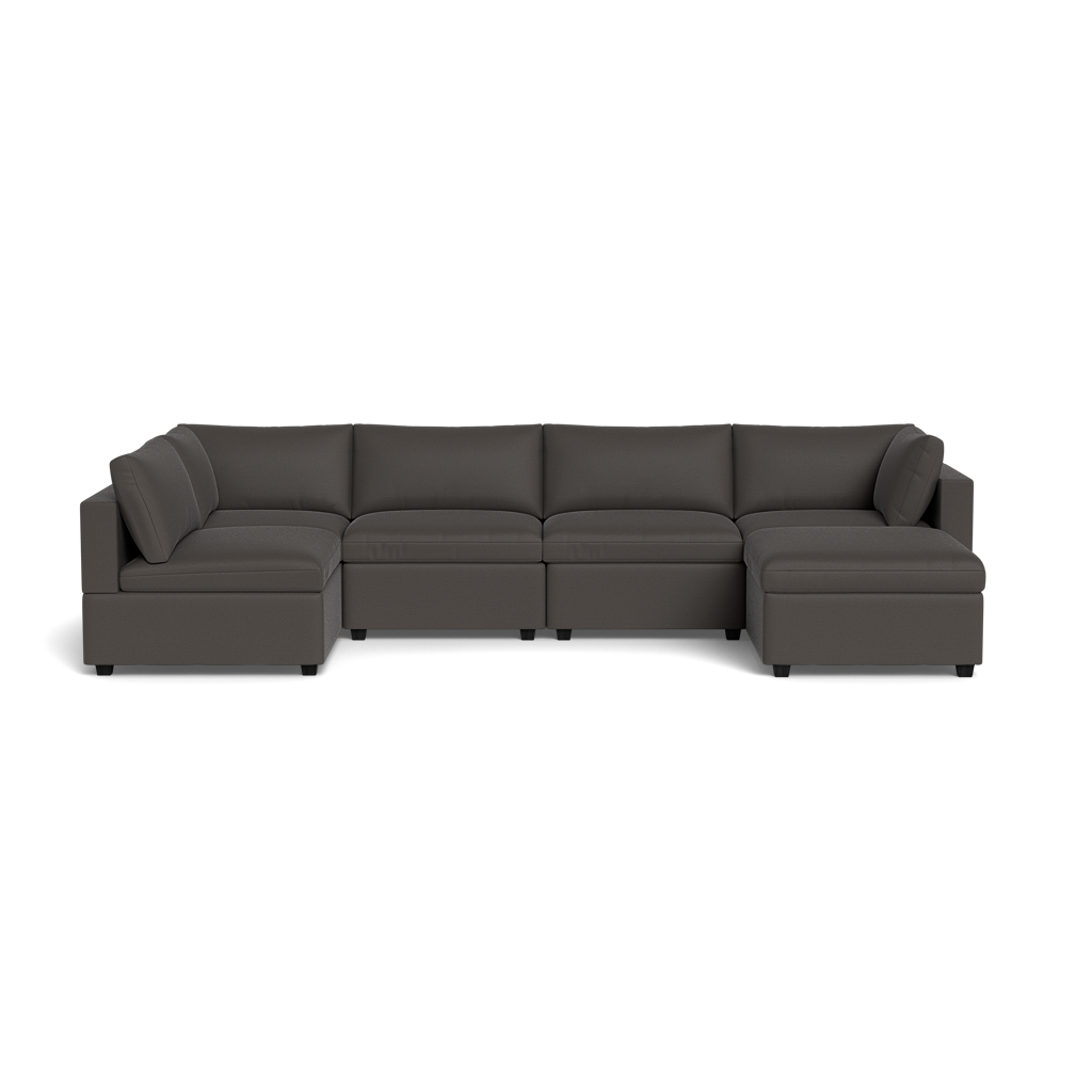 The Kova Box Cushion U-Shape is a large, dark gray sectional sofa with clean lines, seating for five, low armrests, and two chaise lounges at each end, shown against a plain black background.