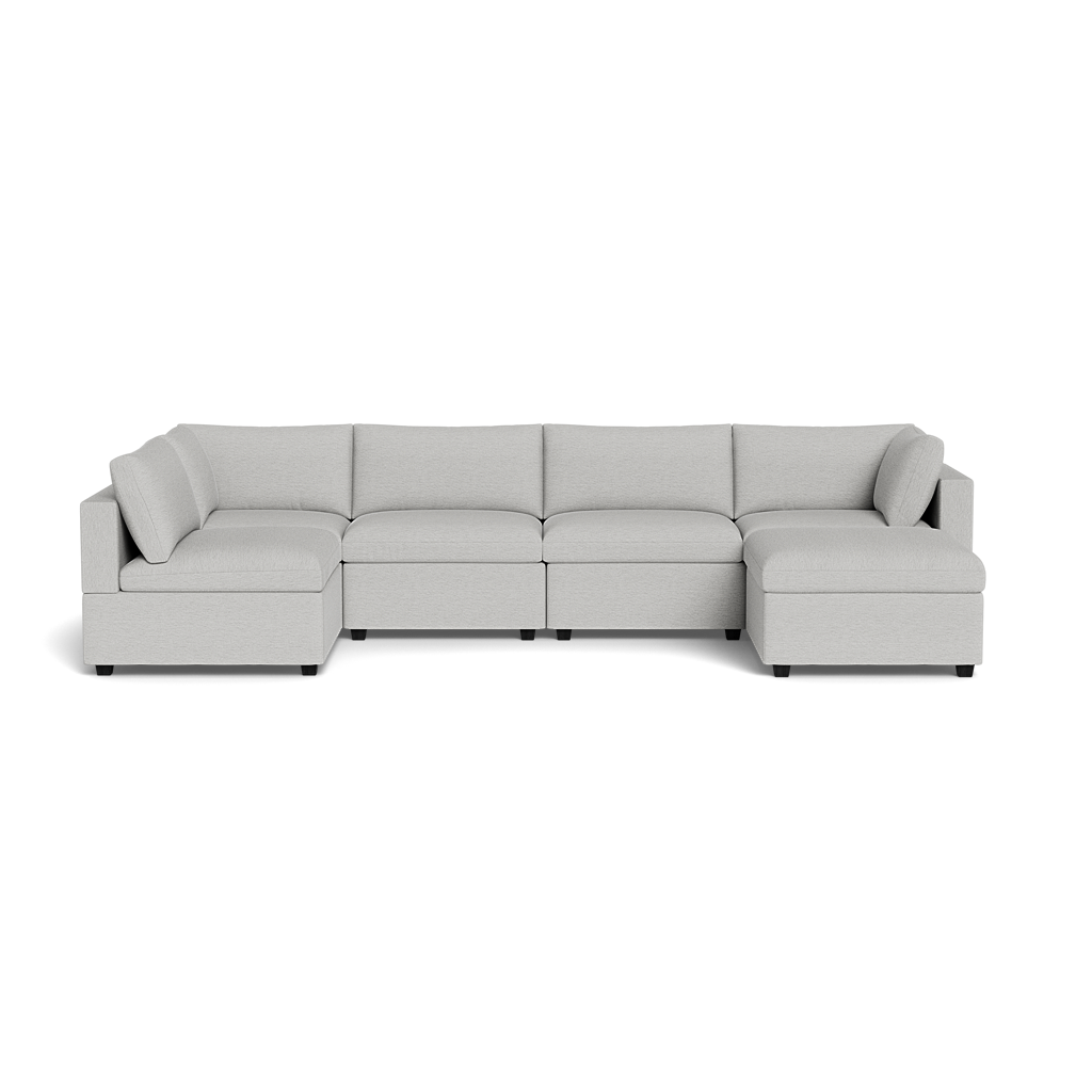 The Kova Box Cushion U-Shape is a light gray sectional sofa with five seat cushions and a low backrest, seen from the front against a black background.