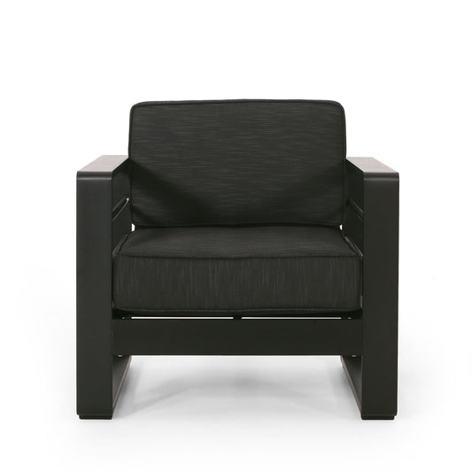 The Maya Bay - Club Chair is a modern black armchair featuring wide armrests, a thick cushioned seat, and a matching cushioned backrest, displayed against a white background.