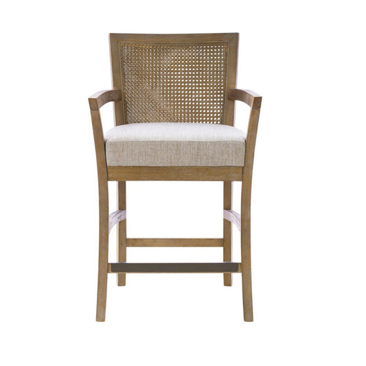 Front view of the Cane Back Counter Stool With Upholstered Seat in Cream / Reclaimed Natural, featuring a wooden frame, woven cane backrest, cream upholstered seat, armrests, subtly curved legs, and a metal footrest.