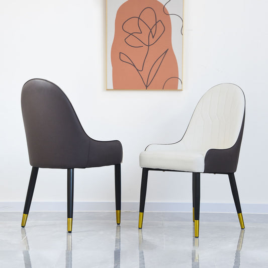 A set of two Modern PU Sponge-Filled Dining Chairs with solid wood and metal legs—one white, one dark grey—stand on a light floor beneath a minimalist framed abstract art piece on a white wall.