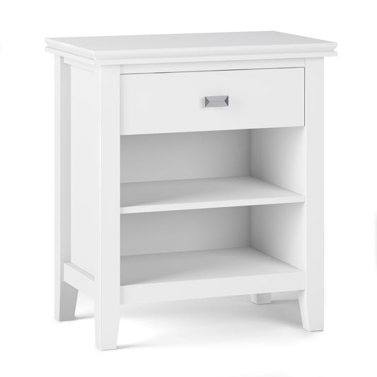 The Artisan - Handcrafted Bedside Table features a white wooden finish, single top drawer with square metal handle, two open shelves below, and a modern design with clean lines and slightly tapered legs.