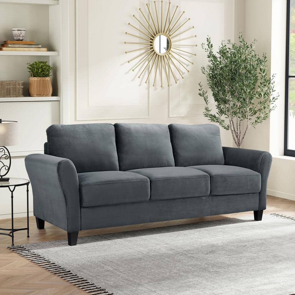 A modern living room featuring the Lifestyle Solutions Wesley 80.3 in. Dark Grey 3-Seater Sofa, a light gray rug, a potted tree, decorative shelves, and a round sunburst mirror on a white wall.