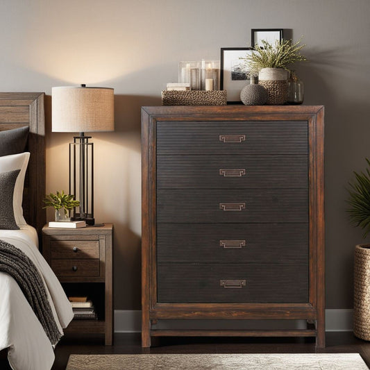 A cozy bedroom corner features a wooden nightstand, modern lamp, partially visible bed, and the Branson - 5 Drawer Chest in two-tone brown, topped with framed art, candles, and potted plants against a taupe wall.
