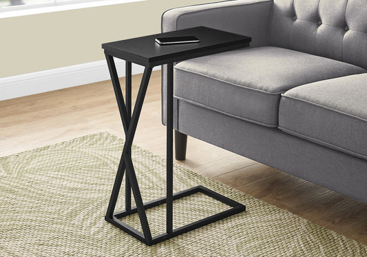 The Accent Table C - Shaped, Contemporary & Modern stands by a gray sofa on a light green textured rug. A smartphone rests atop the small black table with a geometric metal frame; wood floors and a light wall complete the setting.