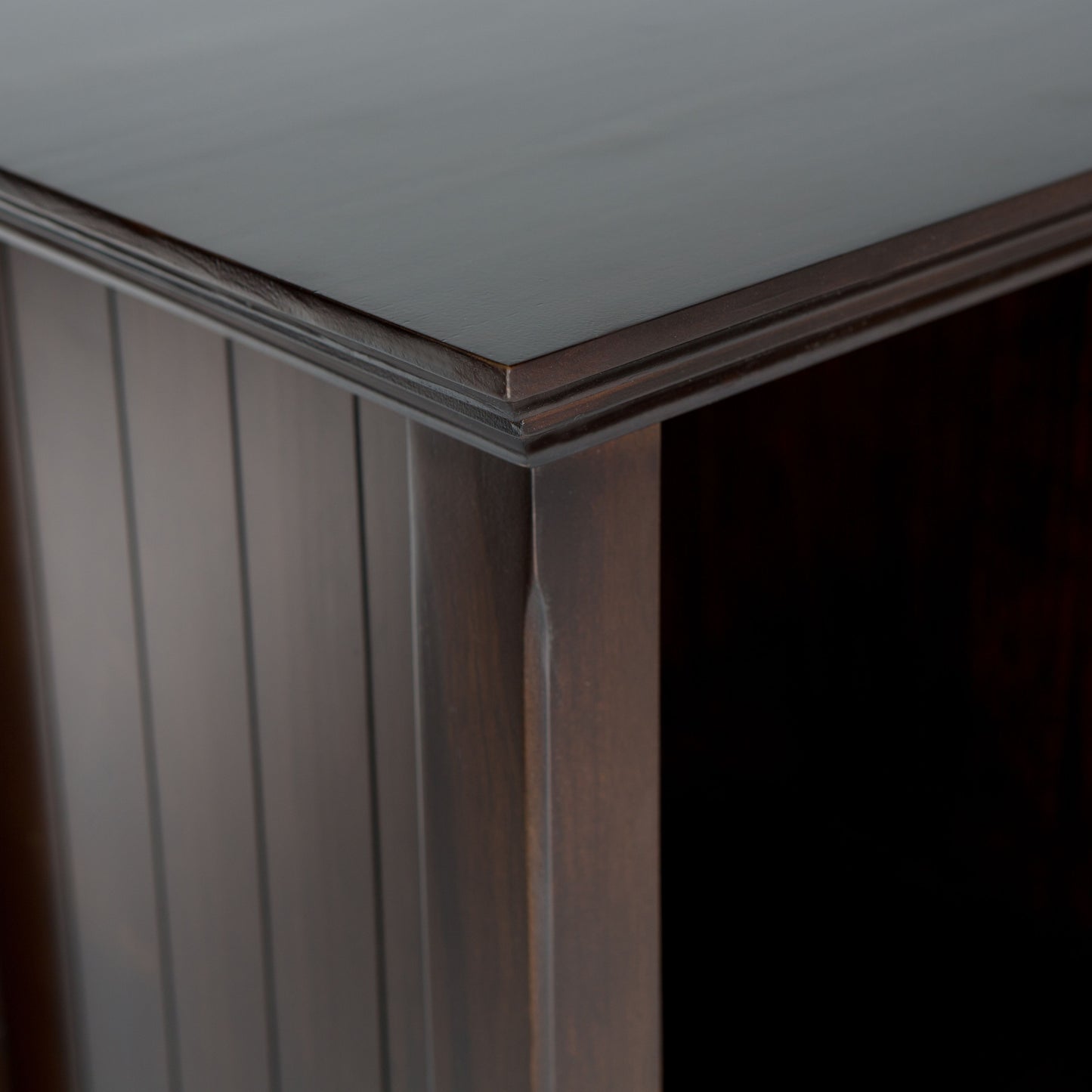 Close-up view of the corner of the Acadian - Handcrafted Cube Storage, showcasing its dark wood finish, smooth polished surface, and vertical panel detailing on the side.