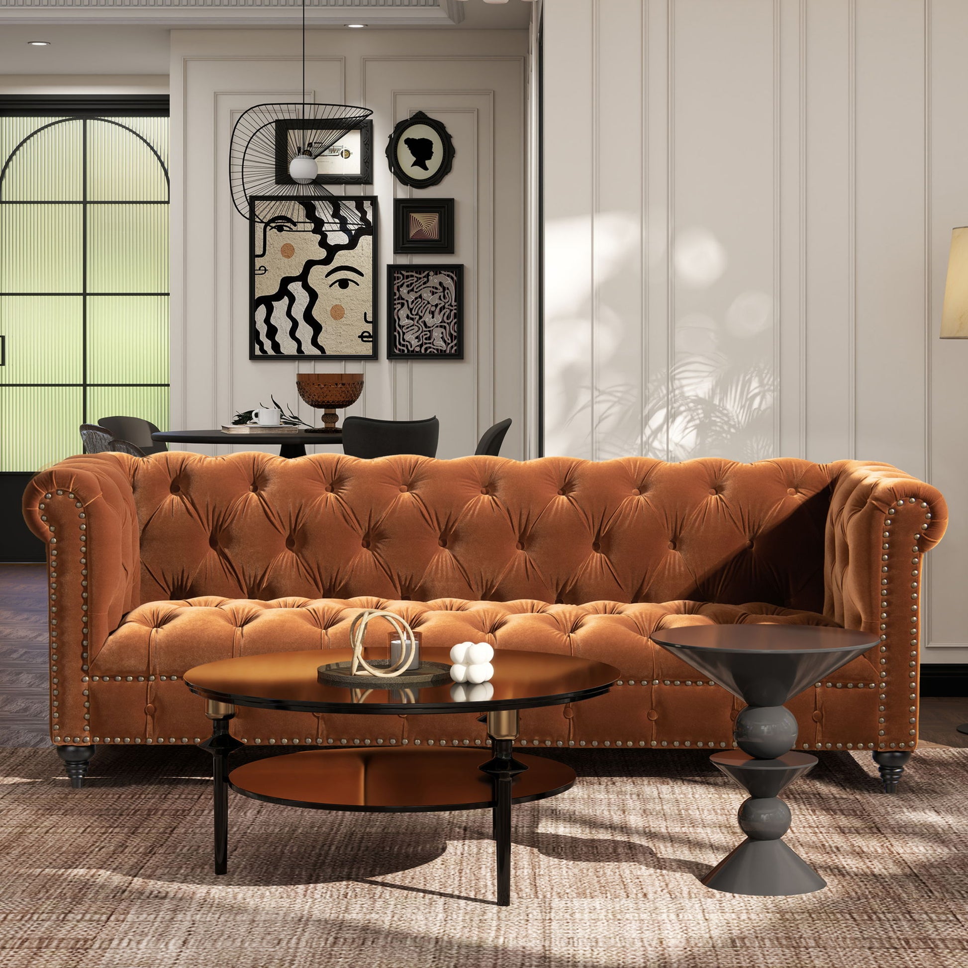 A modern living room with the Alto Tufted Chesterfield Sofa in brown velvet, two round coffee tables, a patterned rug, and abstract art. The background features a dining area and large arched windows.