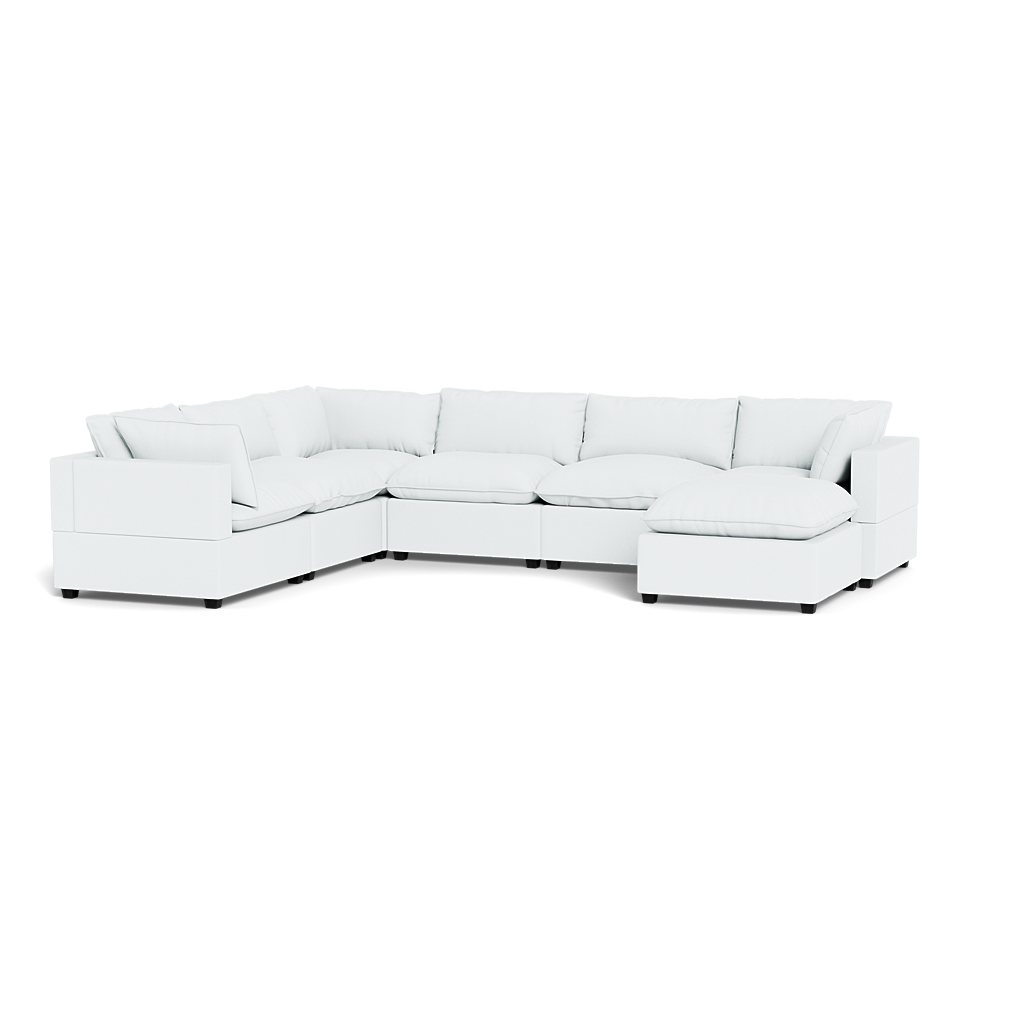 The Kova Pillow Cushion Grand Corner + Ottoman is a spacious, white L-shaped sectional with plush cushions and a chaise lounge, shown against a plain black background.