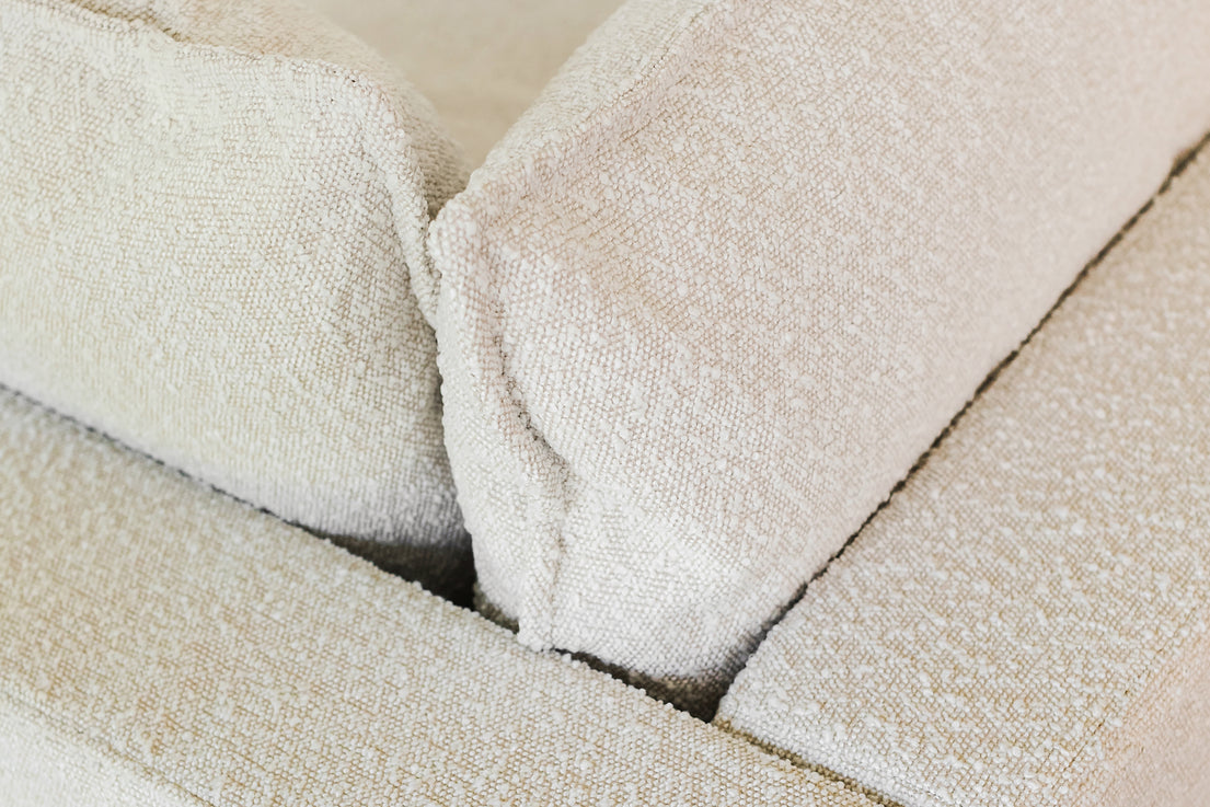 Close-up of the Kova Pit featuring a beige textured fabric with two large back cushions, highlighting its soft and cozy material.