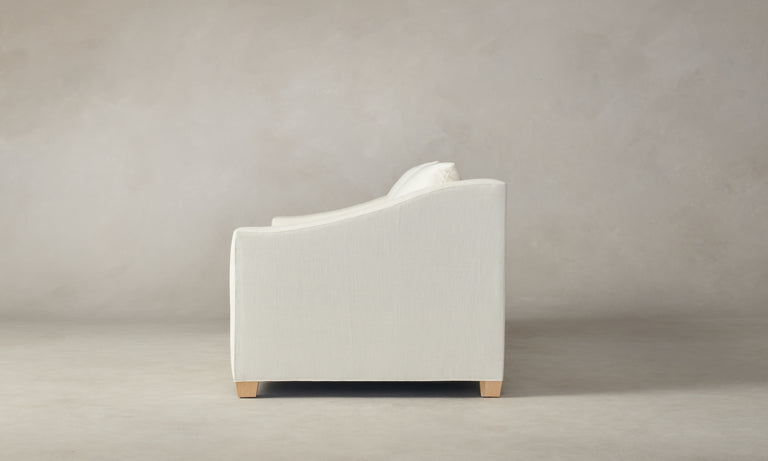Side view of The Sullivan 60" Sofa in Performance Linen Weave, featuring a minimalist design with softly curved armrests and light wooden legs, set against a neutral background.