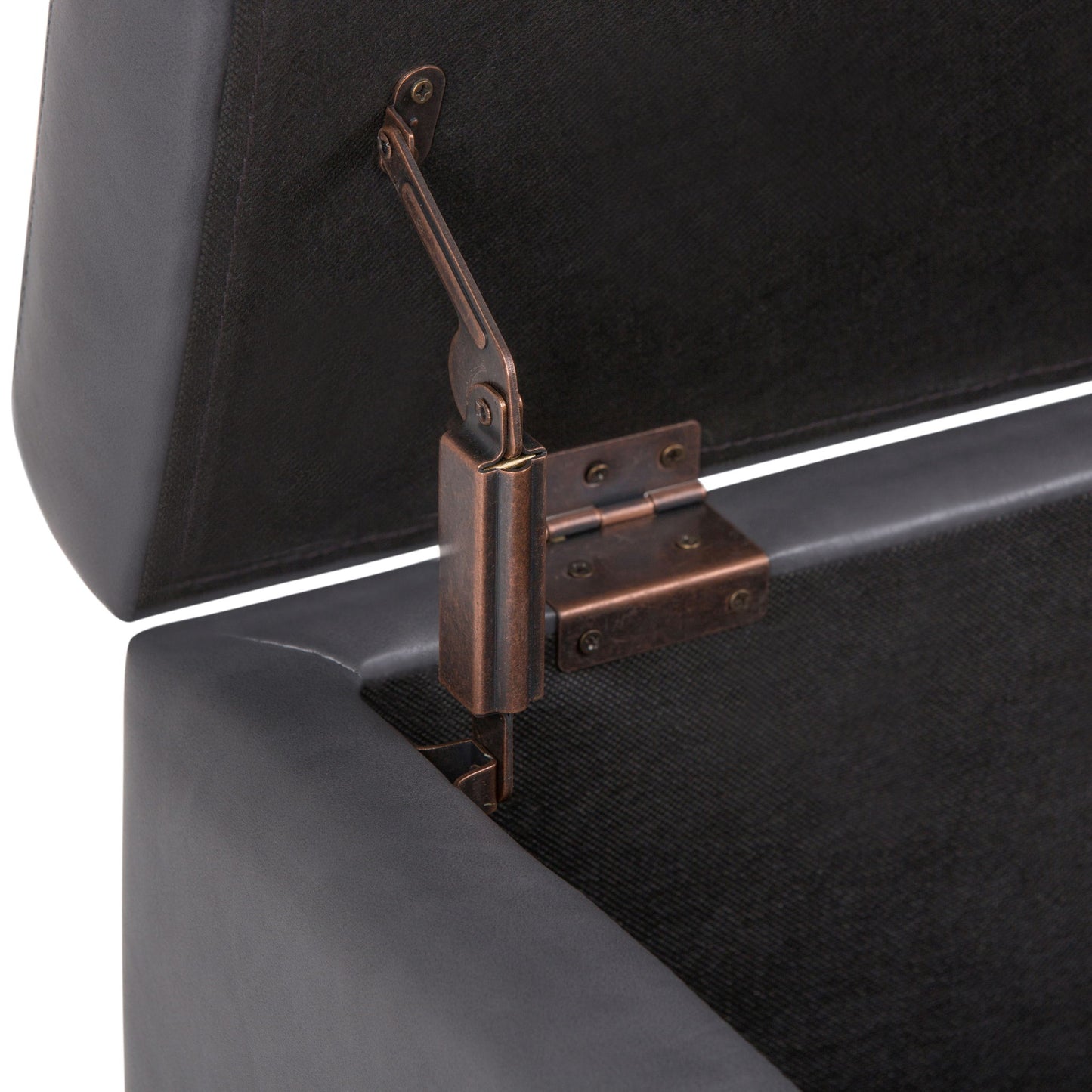 Close-up view of the Hamilton - Upholstered Storage Ottoman in a dark color, shown with its lid open to reveal the metal hinge mechanism attached inside for support.