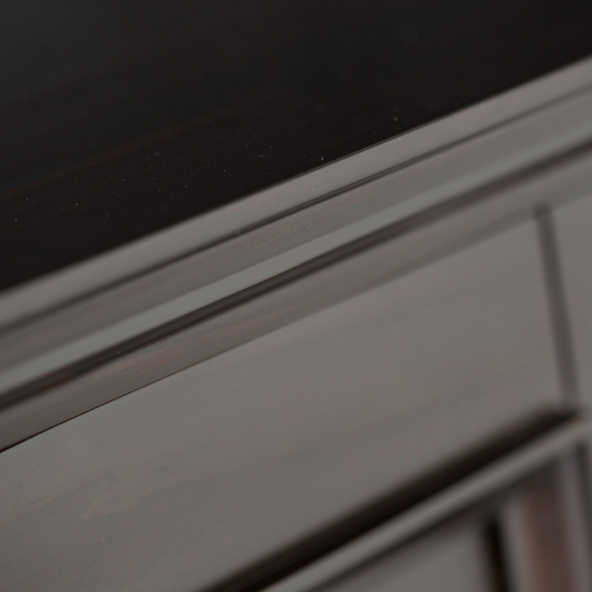 Close-up of the corner of the Amherst - Handcrafted Low Storage Cabinet, showing its dark wood finish, visible grain patterns, and smooth surfaces.