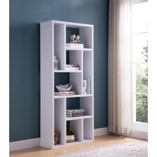 The Versatile Display Cabinet, a modern white piece with asymmetrical shelves, holds books, decor, and a plant. It stands against a teal wall by a window with sheer curtains on a light wood floor.