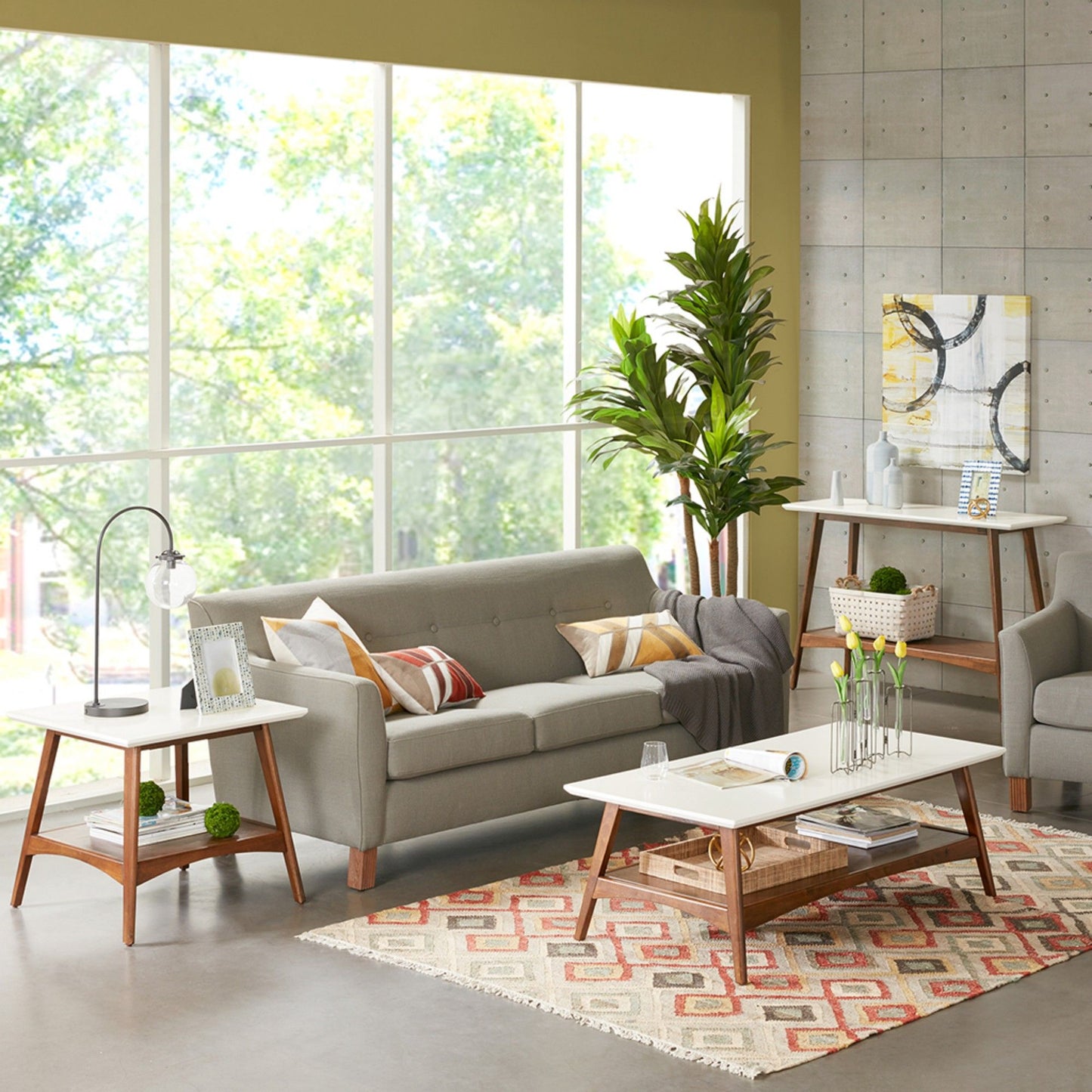 A modern living room with large windows, a gray sofa, white coffee table, Modern Table With Extra Storage, lamp side table, green plants, colorful rug, and abstract art. Natural light fills the inviting space.