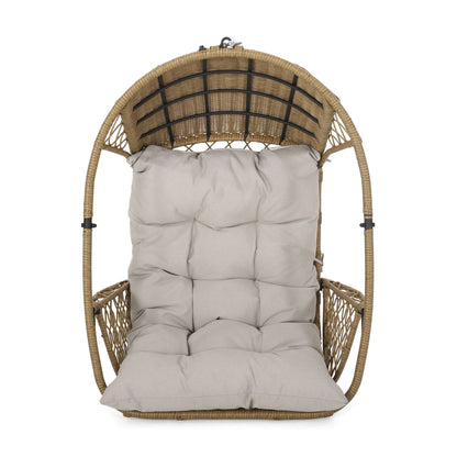 The Malia Wicker Hanging Chair features a dome-shaped frame and a thick tufted beige cushion on the seat and backrest, perfect for comfortable indoor or outdoor lounging.