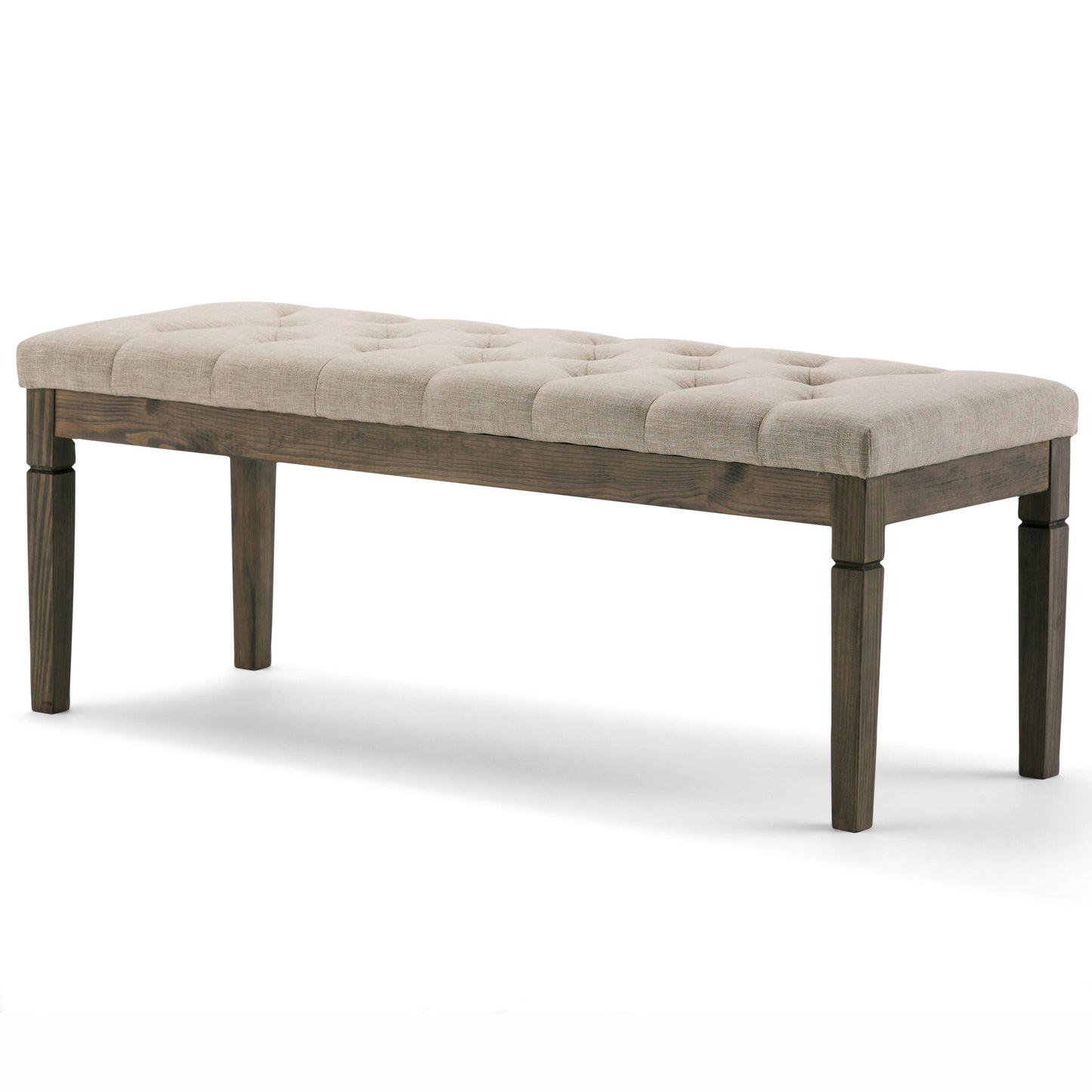 The Waverly Upholstered Tufted Ottoman Bench features a cushioned beige fabric seat with tufting and four dark wooden legs, shown against a plain white background.