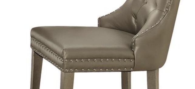 The Kacela Synthetic Leather Side Chair (Set of 2) in Champagne features a tufted backrest, nailhead trim, and wooden legs. Its modern, elegant design is ideal for dining rooms or office spaces.
