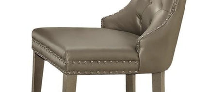 The Kacela Synthetic Leather Side Chair (Set of 2) in Champagne features a tufted backrest, nailhead trim, and wooden legs. Its modern, elegant design is ideal for dining rooms or office spaces.