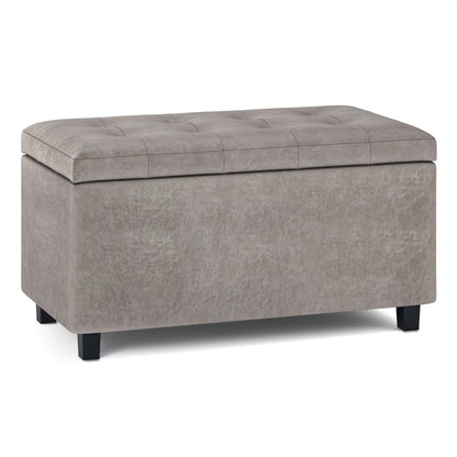 The Cosmopolitan - Upholstered Storage Ottoman, featuring a rectangular gray design with a tufted lid and short black legs, is shown against a white background.