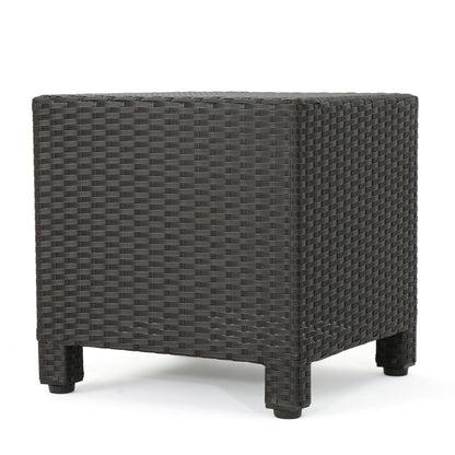 The Puerta Minimalist Style Accent Table features a square shape, dark brown wicker design, and short legs, shown against a white background.