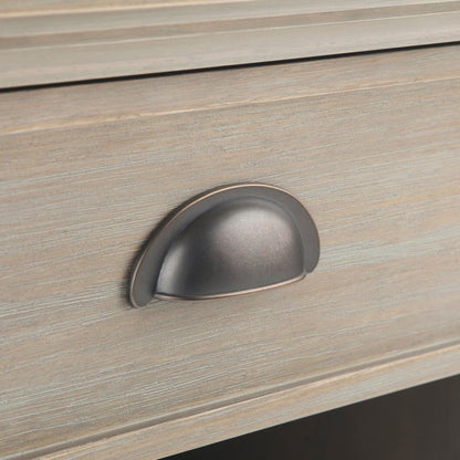 Close-up of the Acadian - Bedside Table, Handcrafted, showing a wooden drawer with a brushed metal cup pull. The light, weathered wood finish highlights horizontal grain and subtle texture.
