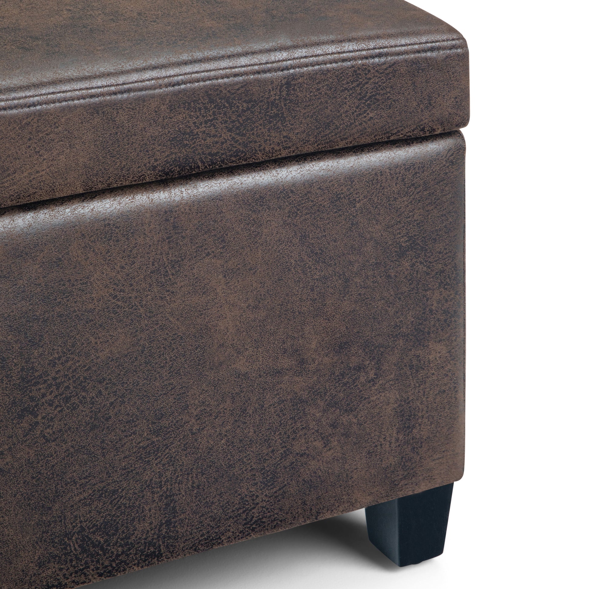 Close-up of the Avalon Storage Ottoman Bench in distressed brown faux leather, featuring visible stitching and short black wooden legs. The surface showcases a textured, weathered look.