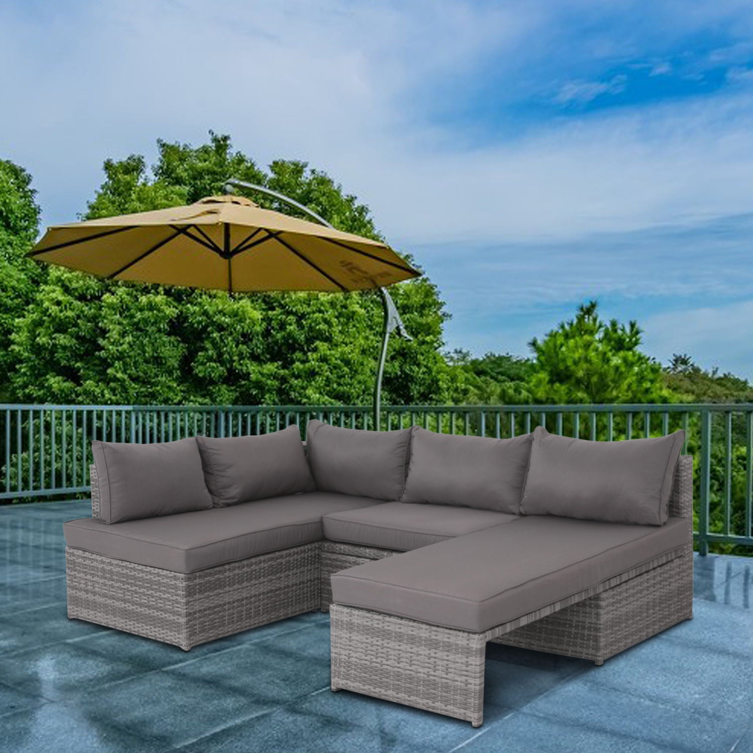 Outdoor patio featuring the Patio Sofa With Cushions - Gray, set on tiles beside a large yellow umbrella, with green trees and blue sky in the background.