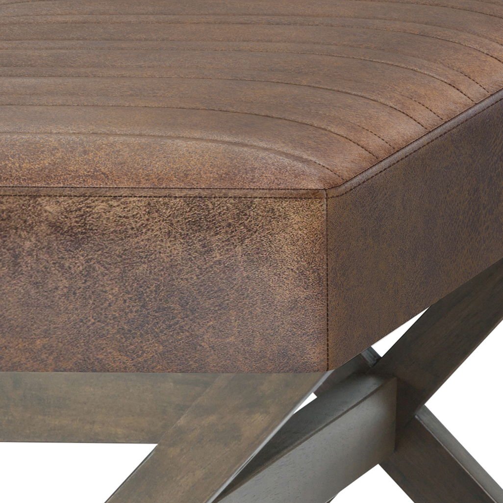 Close-up of the Salinger - Large Upholstered Ottoman Bench, featuring brown leather upholstery with visible stitching and supported by dark wooden X-shaped legs.
