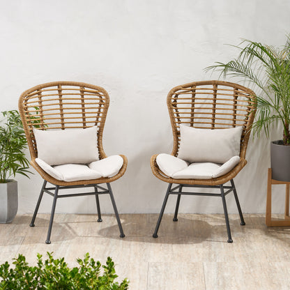 Two Calypso outdoor chairs with water-resistant cushions and iron frames sit side by side on a light tiled floor, surrounded by green potted plants against a white wall.
