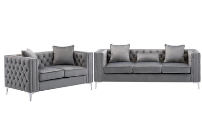The Lorreto Velvet Fabric Living Room Set includes two modern gray sofas with tufted backs and arms, silver nailhead trim, metal legs, matching cushions, and decorative pillows for extra comfort.
